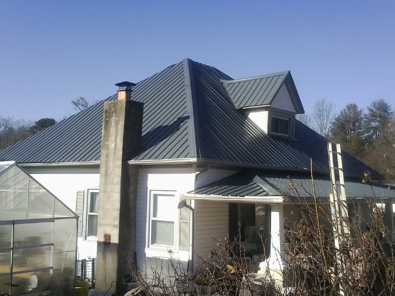 Dark blue standing seam metal roof on a white farmhouse with dormer — Slate & Tile Roof Repair by Roofing Brothers in Mount Pocono