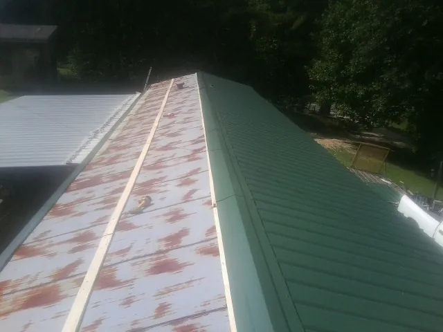 Old rusted panels beside newly installed green metal roofing — Wind Damage Roof Repair by Roofing Brothers in Mount Pocono