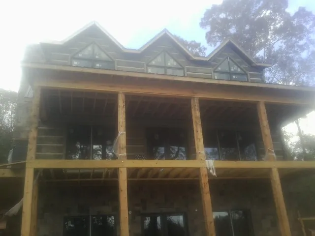 Dormers and porch framing on a large log home under construction — Roof Coating work by our crew in Mount Pocono