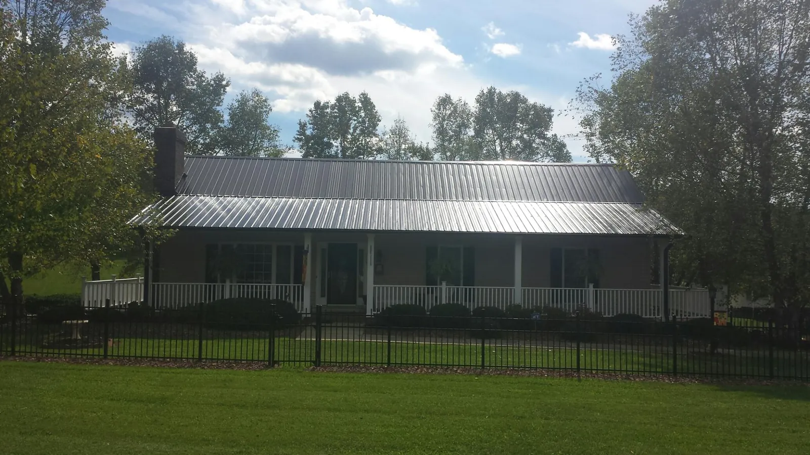 Gray metal roof on a brick ranch with a full width front porch — Gutter Guard Installation work by our crew in Mount Pocono