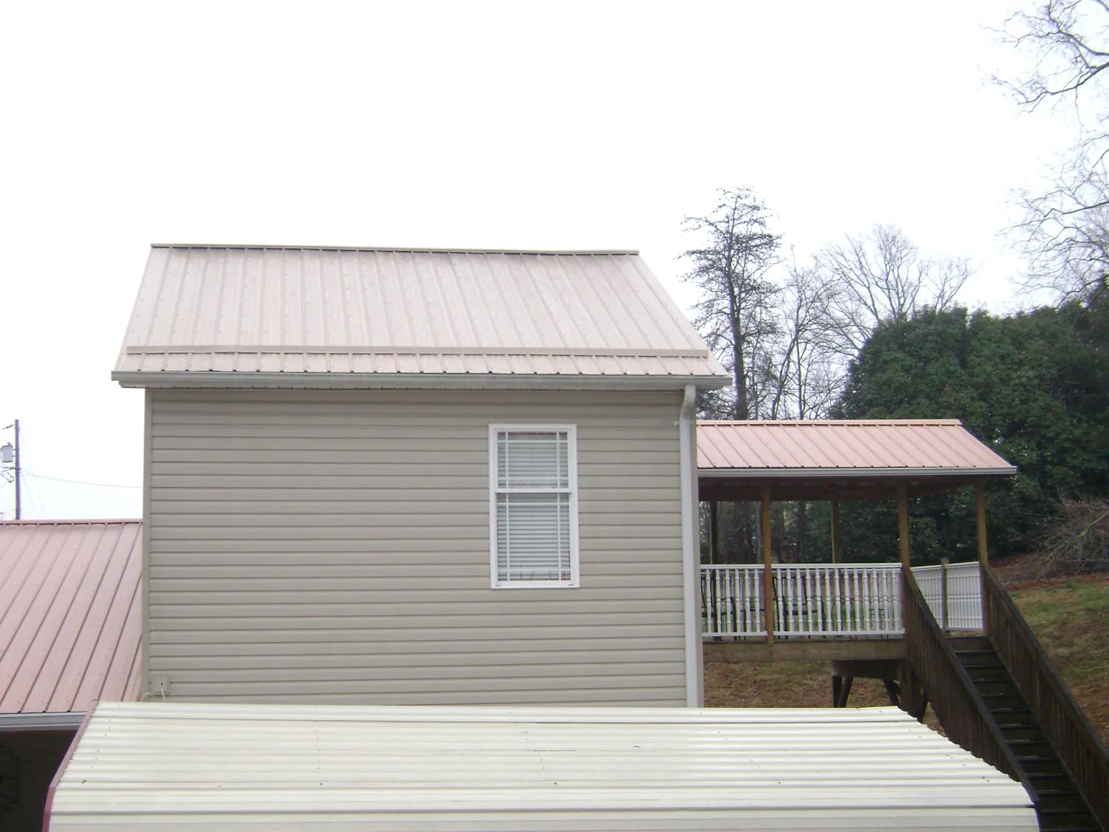 Tan metal roofs on a two story addition and attached porch, from a Roof Replacement job in Mount Pocono