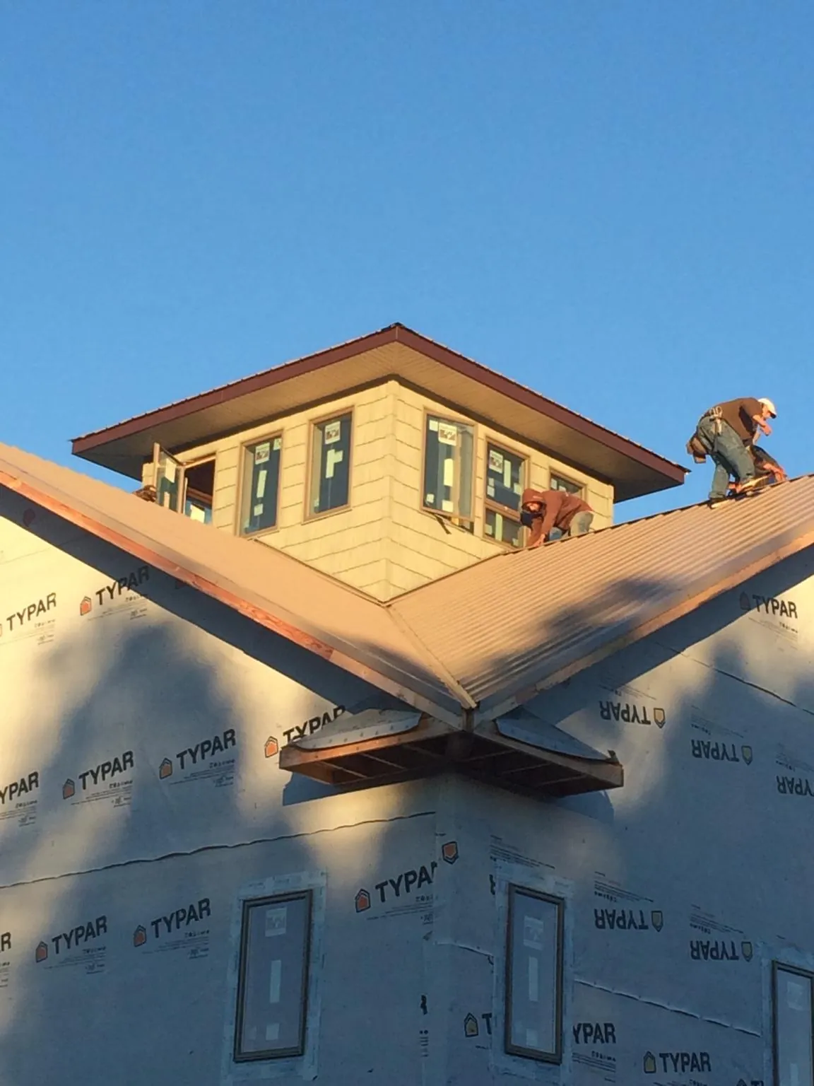 Roofers working around a rooftop cupola on a new metal roof at sunset — Roof Waterproofing in Mount Pocono by Roofing Brothers